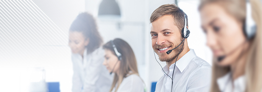 Mai multe persoane dintr-un call center, cu un bărbat zâmbind în prim-plan.